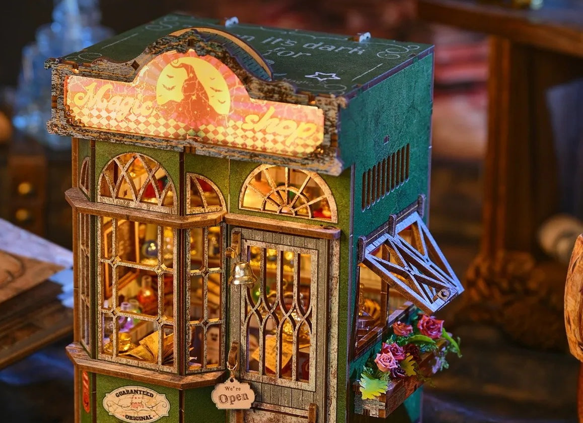 Enseigne lumineuse et vitrine du book nook boutique de magie, avec sa jardinière de roses
