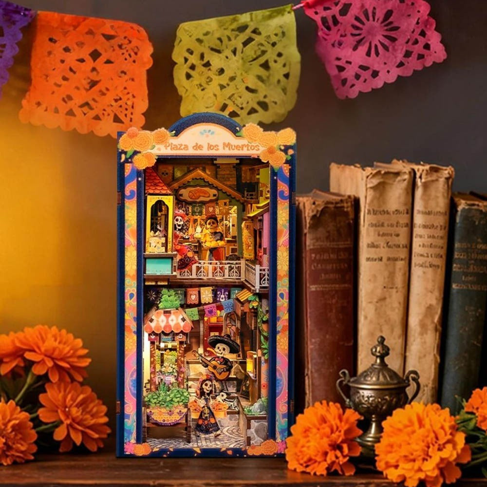 Book nook fête des morts mexicaine sur une étagère entre livres anciens et papel picado