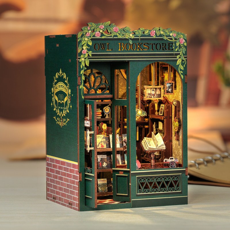 Book nook librairie à façade verte et lierre éclairé sur un bureau