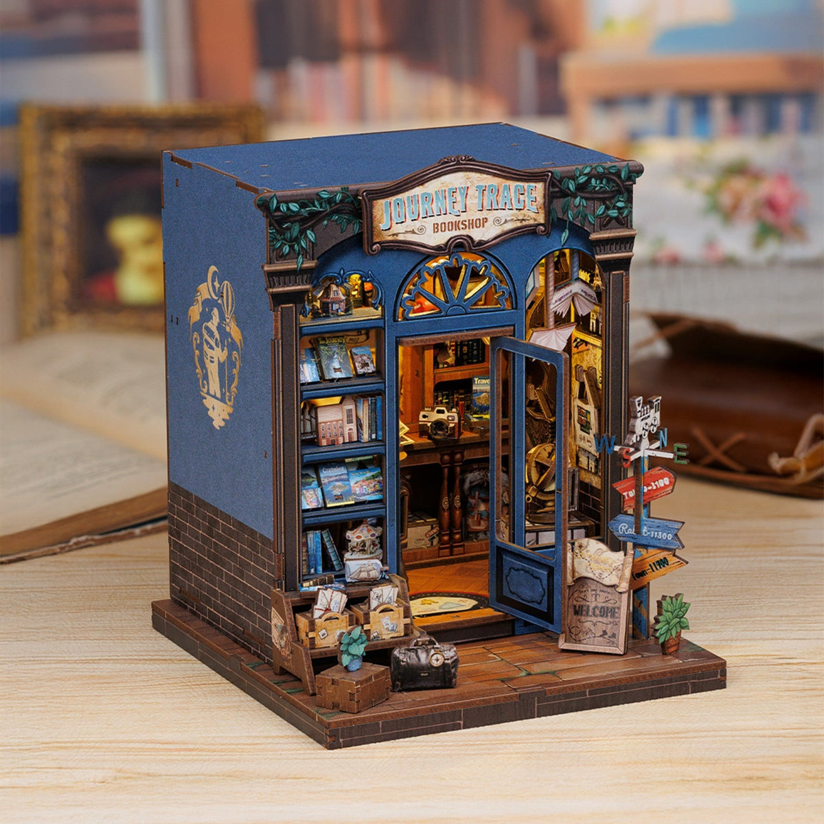 Book nook librairie du voyage posé sur une table en bois, briques et façade bleue
