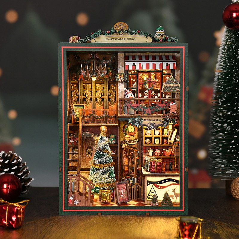 Book nook Noël boutique de cadeaux, vue de face à côté d'un sapin