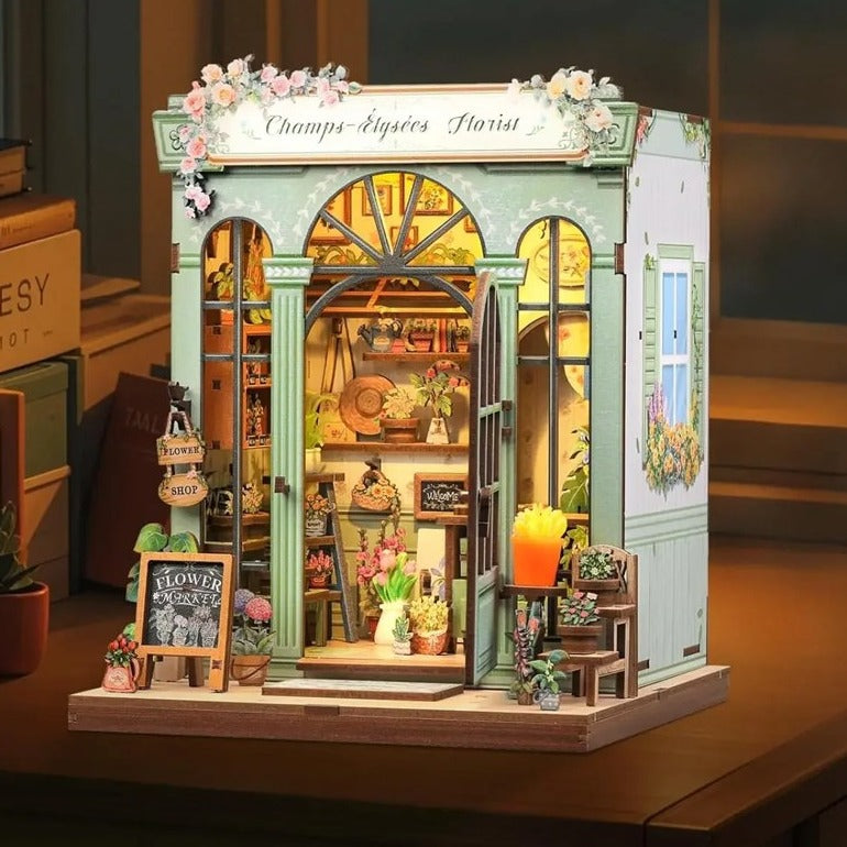 Book nook fleuriste parisien éclairé, porte ouverte, sur un bureau le soir