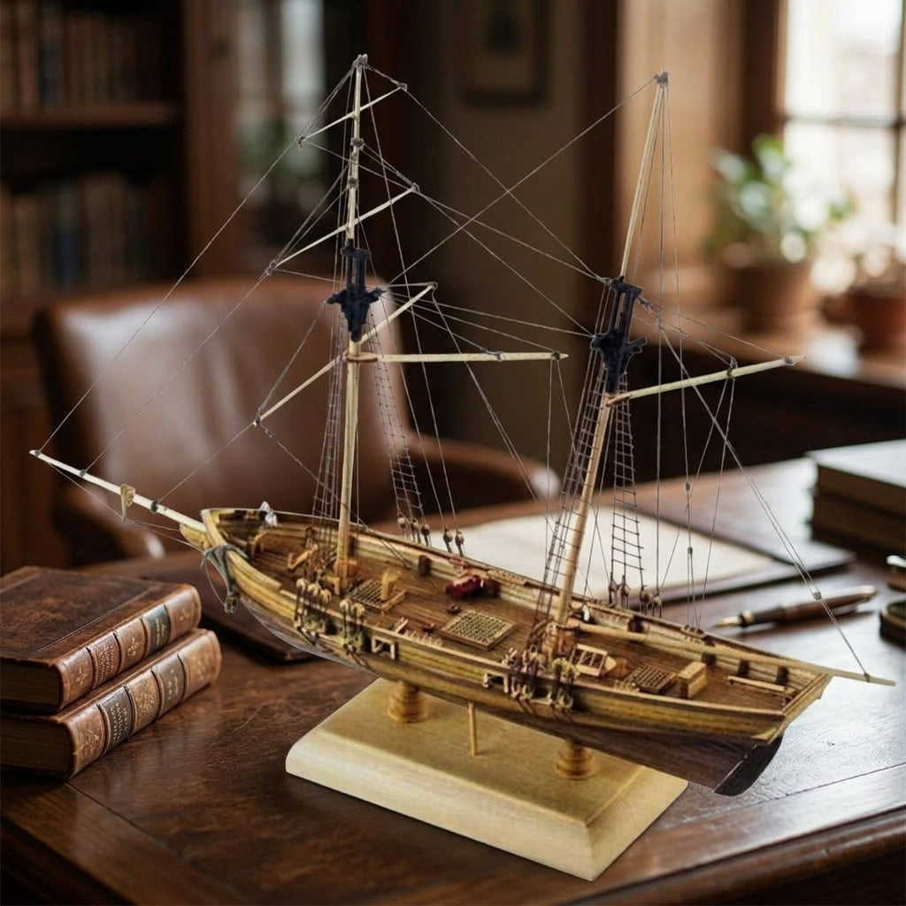 Maquette de goélette en bois posée sur un bureau à côté de livres